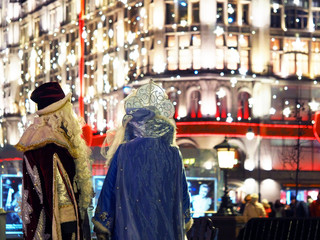 Obraz premium Santa Claus or Father Frost and Snow Maiden on the background of the festive night city. Celebration of New Year in Moscow, Russia