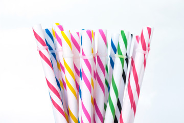 Striped drink straws in different colors on white background.