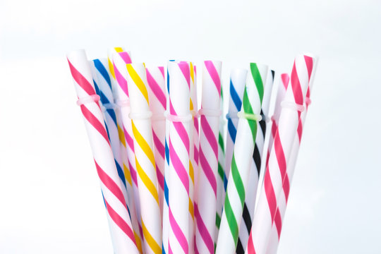 Striped drink straws in different colors on white background.