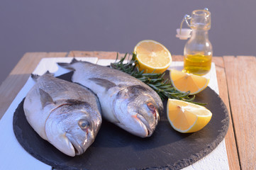 dorado fish on a black plate with lemon, rosemary