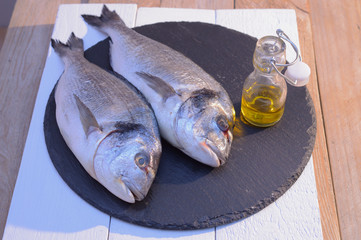 dorado fish on a black plate with olive oil bottle