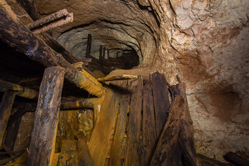 Underground abandoned gold iron ore mine shaft tunnel gallery passage with timbering wooden