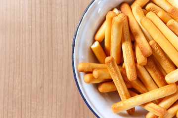 bread sticks on bowl on wooden background.