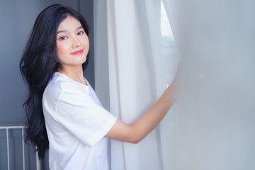 Woman stretching in bed after waking up, back view. Woman sitting near the big white window while stretching .she happy and smile.