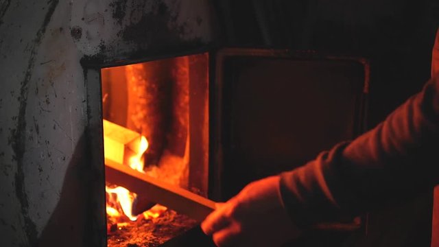 man throws wood in the stove