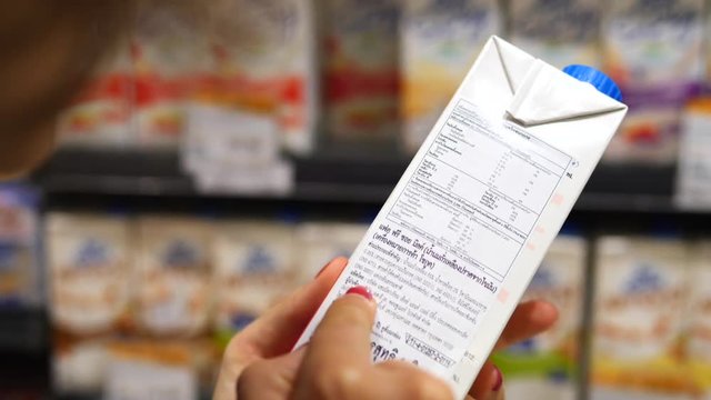 Woman Reading Ingredients On Product Label While Shopping In Supermarket. Closeup.
