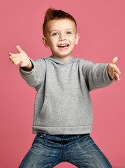 Young boy kid in grey hoodie pointing one finger at the corner smiling isolated on pink 