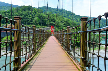 the walkway on red hanging bridge or suspension bridge above the green river in the valley, Wulai, Taiwan