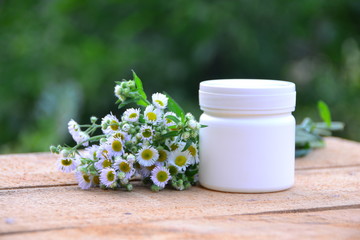 Fototapeta na wymiar Can for ointment in nature with chamomile flowers