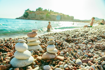 Fototapeta na wymiar balanced rocks at seaside. rocky beach on sunset. kids swimming on background