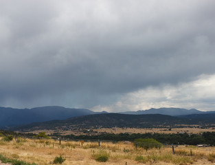 Mountain summer landscape with dark cloudy sky and land with dry grass. In the mountains before the...