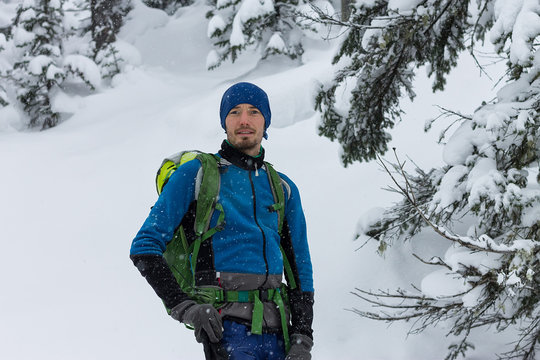 portrait of male freerider in snowfall in winter forest