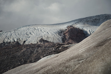 Mountain landscape dusty dirty volcanic slope with cracked melting glacier. Global warming....