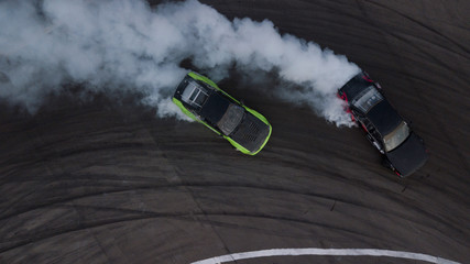 Aerial view drift battle, Two cars drift battle on race track with smoke. - obrazy, fototapety, plakaty