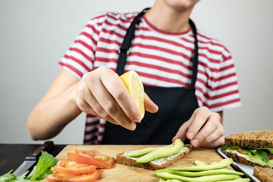 Making raw food snack. Female hands squeeze lemon juice onto avocado sandwich - Powered by Adobe