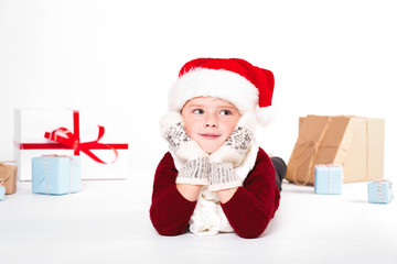 Obraz na płótnie Canvas Merry Christmas and happy New year! Cute happy little boy holding present. Kid enjoy holiday with santa hat. Portrait kid on light background isolated. Happy Child with place for text