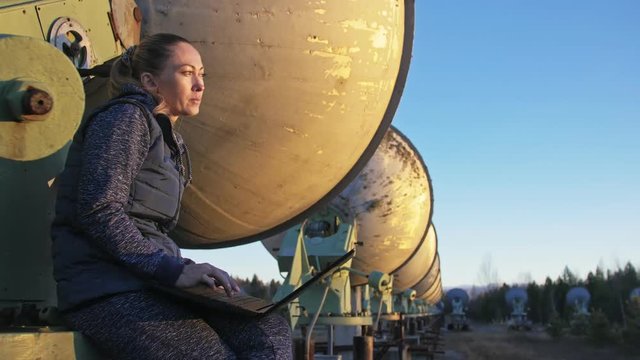 Woman student operator of institute of Solar Terrestrial Physics monitors communication equipment in notebook. Unique array solar radio telescope. Sun Solar Radio Telescope. The 'Quasar' observatory