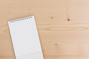 White blank paper desk spiral calendar on wood background..