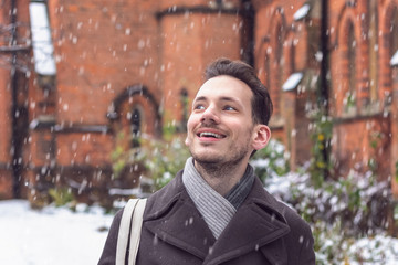 Happy smiling man amazed by falling snow on London street