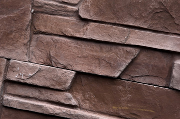 Stone wall of natural stones in different sizes. Rustic stone veneer in shades of brown color. Wall covering with natural stones