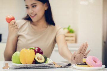Young beautiful woman take care her health by eating salad and fruit instead of eating fat and...