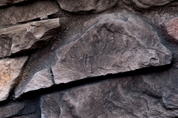 Grey rustic stone in stone wall of natural stones in different sizes and different colors. Rustic stone veneer in shades of brown color