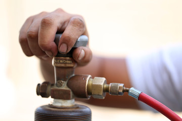 Closeup man's hand operating valve of gas cylinder for welding