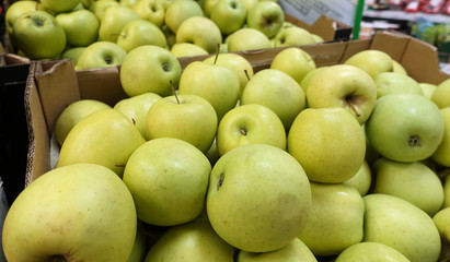 Fresh Golden Delicious juicy whole apples for sale in a store in boxes.