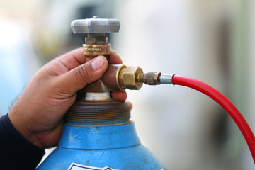 Closeup man's hand operating valve of gas cylinder for welding