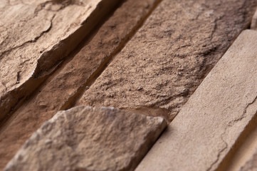 Stone wall of natural stones in different sizes. Rustic stone veneer in shades of brown color. Wall covering with natural stones