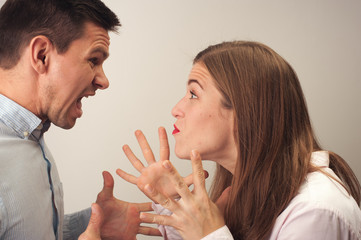 Close-up profiles of emotional distressed angry couple man and woman wearing casual light clothes shouting during the quarrel expressive bright gestures with hands.