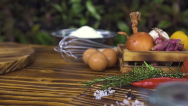 Food composition from colorful vegetables, seasoning, flour and eggs on wooden table. Vegetale background tracking shot. Ingredient for cooking food on kitchen table. Healthy nutrition and dieting.
