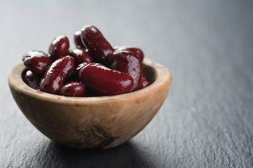 red canned beans in wood bowl on slate background