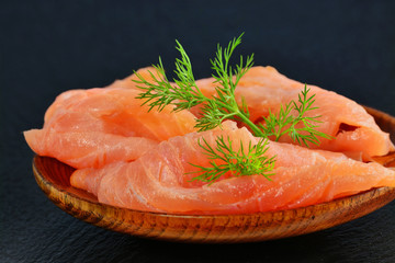 Thinly sliced smoked salmon fillet, on plate over black slate platter