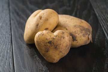 fresh raw potatoes on black wood background