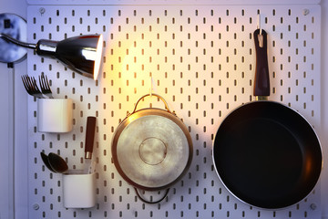 kitchen utensils hanging on the wall and wall lamp