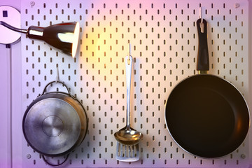 kitchen utensils hanging on the wall and wall lamp