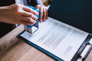 Business woman sitting with brass scale at lawyer desk, Lawyer working hand holding automatic stamp important documents in office. lawyer and law ,judiciary and legislature courtroom legal concept.