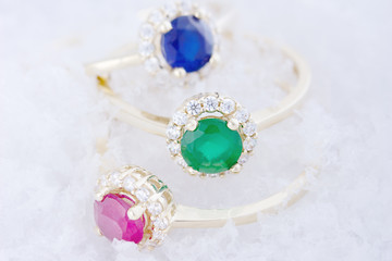Collection of golden rings with colorful gems on snow background. Gemstones collection jewelry