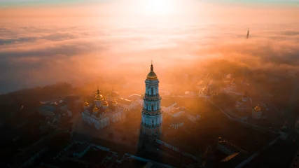 Fotobehang Aerial view of Kiev Pechersk Lavra at dawn and the city covered with thick fog in the background. © LALSSTOCK