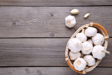 Fresh garlic in basket on a grey wooden background