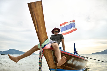 Obraz premium Tanned man with stubble is sailing on colorful boat