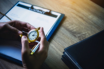 lawyer women looking at vintage pocket watch during working with documents contract in office. Legal law and justice concept.