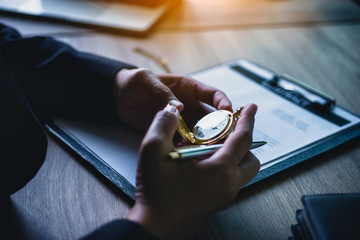 lawyer women looking at vintage pocket watch during working with documents contract in office....
