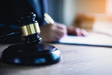 Close up of hand lawyer working signing contract paper with wooden gavel judge in the office. lawyer and law ,judiciary and legislature courtroom legal concept.