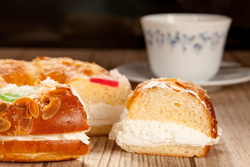 Spanish typical dessert of epiphany  cut piece close-up and porcelain cup on black