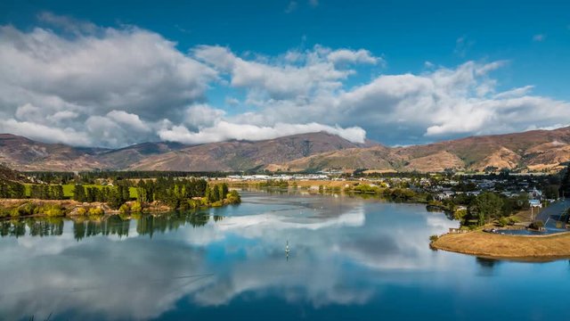 Beautiful dramatic clouds flying above mountains in Central Otago region in New Zealand. Scenic town of Cromwell in the view. Timelapse video.