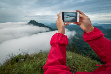 Young woman using smart phone take a photo mountain view