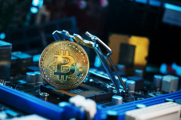 Golden Bitcoin Cryptocurrency on computer circuit board CPU. Macro shot.