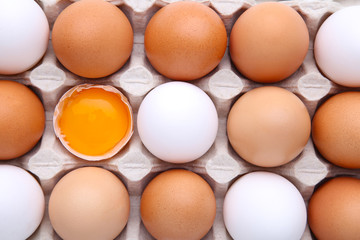 Raw eggs in carton for background. Chicken egg is half broken among other eggs